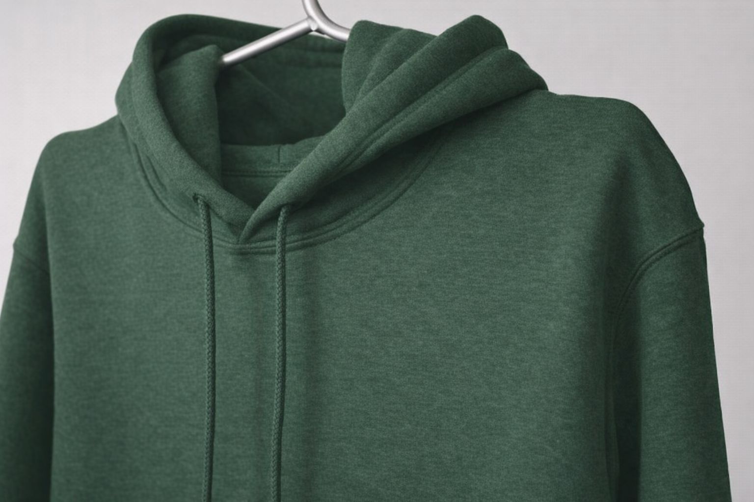 Närbild på en mörkgrön huvtröja hängande på en silvergalge.